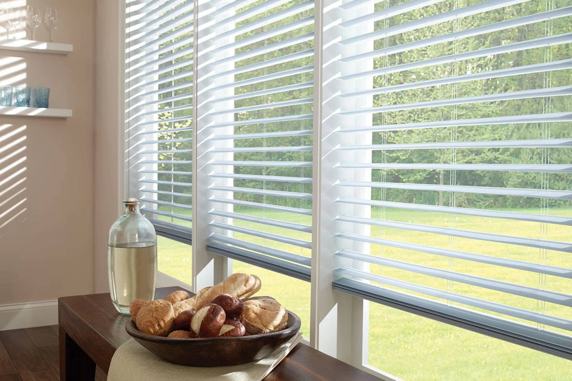 White Venetian blinds with sunlight through the slats