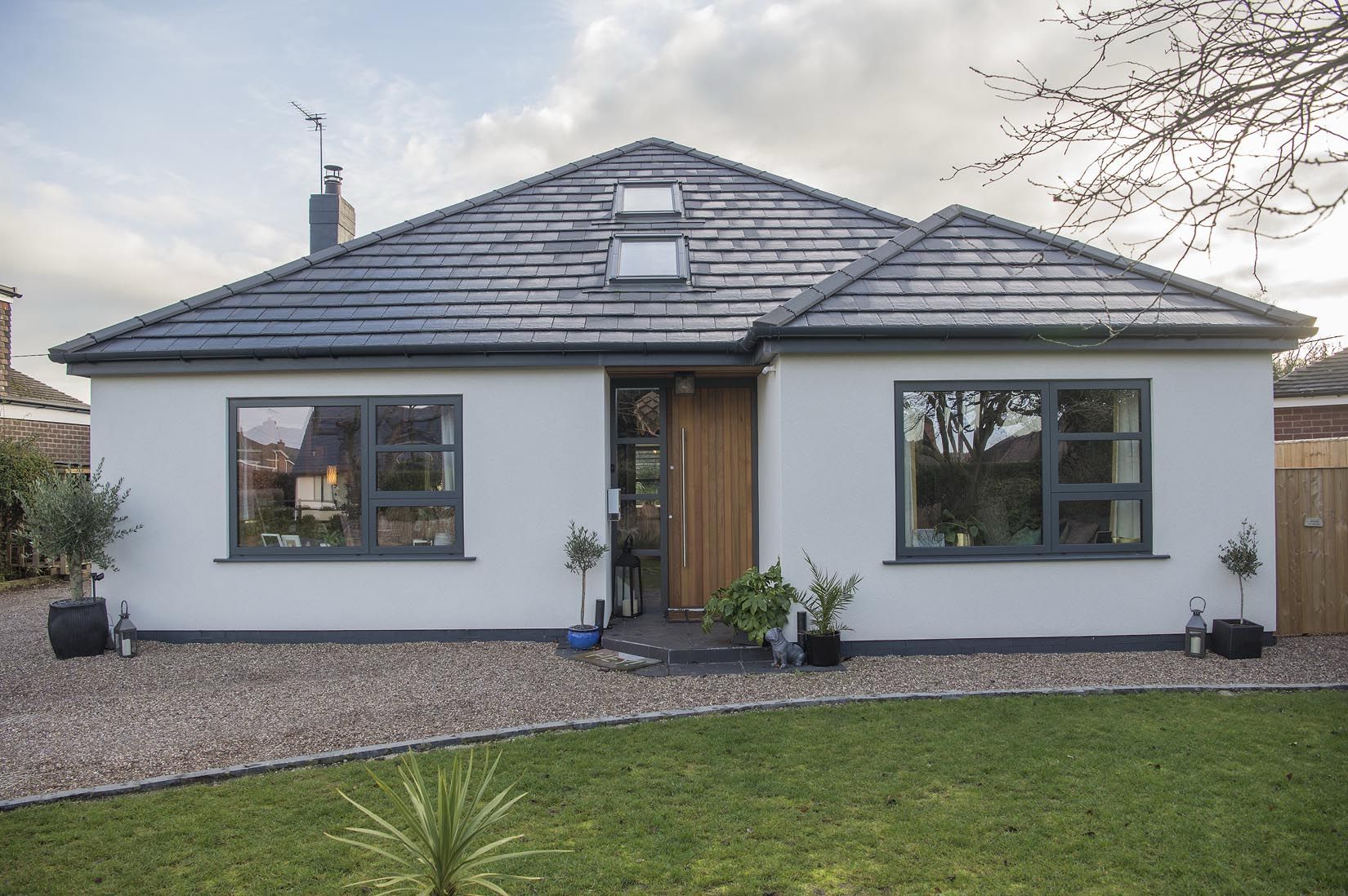 Grey windows on a white bungalow with a timber front door